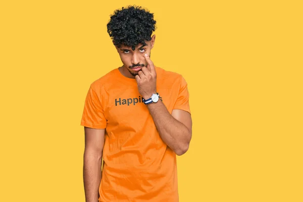 年轻的阿拉伯男子穿着T恤 脸上挂着快乐的字条 指着你的眼睛看着你的动作 怀疑的表情 — 图库照片