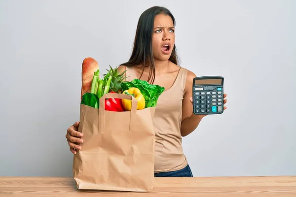 Hermosa Mujer Hispana Sosteniendo Comestibles Calculadora Enojada Loca Gritando Frustrada —  Fotos de Stock