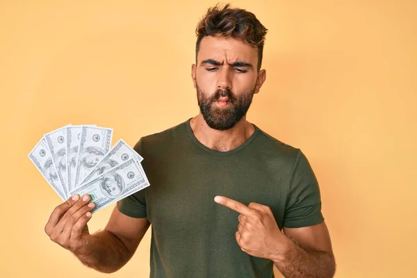 Young Hispanic Man Holding Dollars Making Fish Face Mouth Squinting — Stock Photo, Image