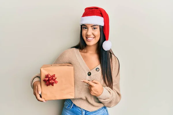 Jovem Bela Menina Hispânica Vestindo Chapéu Natal Segurando Presente Sorrindo — Fotografia de Stock