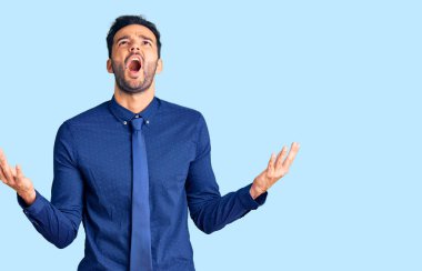 Genç, yakışıklı, iş kıyafetleri giymiş çılgın ve deli gibi bağıran saldırgan bir ifade ve kollarla bağıran bir İspanyol. hüsran kavramı. 