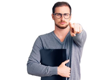 Elinde iş dosyası tutan yakışıklı beyaz bir adam kamerayı ve seni işaret ediyor. Kendine güveni tam bir jest. 