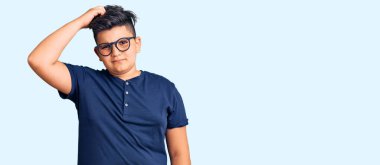 Günlük kıyafet ve gözlük takan küçük çocuk soru sormayı merak ediyor. Şüpheyle kararsız, kafa kafaya düşünerek. Düşünceli kavram. 