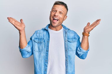 Sıradan kot ceket giyen yakışıklı kaslı adam çılgınlığı kutluyor ve başarıya hayret ediyor kolları açık ve gözleri açık heyecanla bağırıyor. Kazanan konsept 