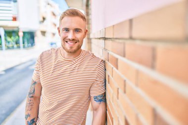 Genç İrlandalı gülümseyen mutlu adam şehrin duvarına yaslanıyor..