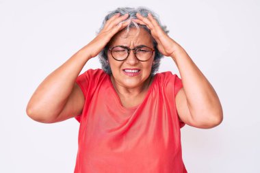 Yaşlı Latin asıllı, gri saçlı, günlük kıyafetler giyen, gözlüklü, baş ağrısı çeken, çaresiz ve stresli bir kadın. Çünkü acı ve migren. Eller başının üstünde.. 