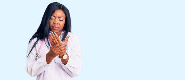 Genç Afrikalı Amerikalı kadın doktor steteskopu takıyor. Ellerinde ve parmaklarında ağrı var. Eklem iltihabı. 