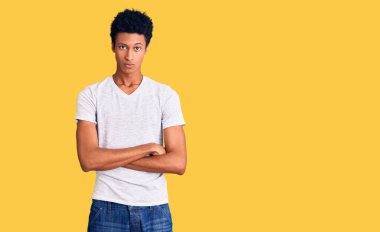 Sıradan beyaz tişört giyen, kuşkucu ve gergin genç Afro-Amerikalı adam. Yüzünde çapraz kollu tasvip etmeyen ifade. negatif kişi. 