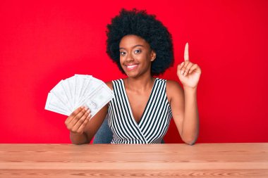 Elinde dolar tutan Afrikalı genç bir Amerikalı kadın bir fikre ya da soru işaretine şaşırdı ve mutlu bir yüzle işaret etti. 