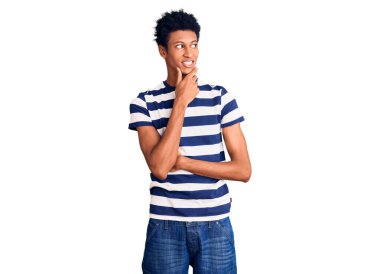 Elleri çenesinde gündelik giysiler giyen genç Afro-Amerikan bir adam soru soruyor, düşünceli bir ifade. Düşünceli bir yüzle gülümsüyor. şüphe kavramı. 
