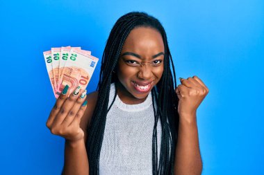 Avro banknotları tutan Afrikalı genç bir Amerikalı kadın gururla bağırıyor, zaferi kutluyor ve kollarını kaldırdığı için çok heyecanlı. 