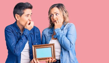 Elinde boş bir çerçeve olan iki kadın gergin ve gergin görünüyor. Ağzı tırnak yiyen ellerle. anksiyete. 