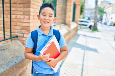 Sevimli öğrenci gülümsüyor. Şehrin caddesinde kitap tutarken mutlu..