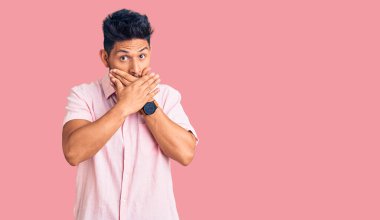 Gündelik tişört giyen yakışıklı Latin Amerikalı genç adam ağzını yanlışlıkla ellerle kapatırken şok oldu. gizli kavram. 