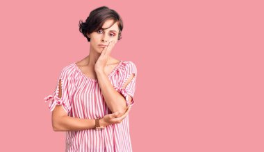 Kısa saçlı, günlük giysiler giyen, yorgun görünen ve depresyondan sıkılmış kollarını kavuşturan güzel bir genç kadın.. 