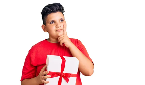 Маленький Хлопчик Тримає Подарунок Серйозне Обличчя Думаючи Про Питання Рукою — стокове фото