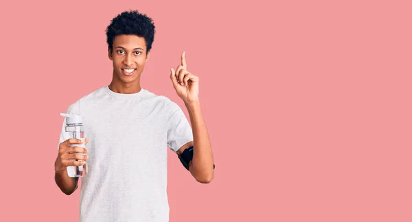 Young African American Man Wearing Sportswear Holding Water Bottle Surprised — Stock Photo, Image