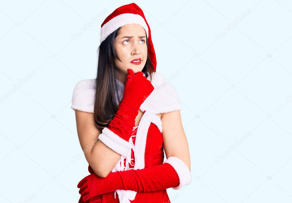 Young beautiful caucasian woman wearing santa claus costume thinking worried about a question, concerned and nervous with hand on chin 