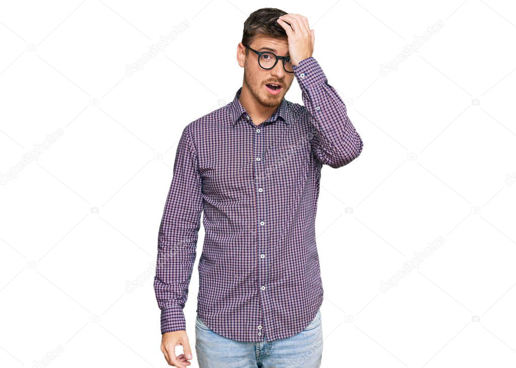 Handsome caucasian man wearing casual clothes and glasses surprised with hand on head for mistake, remember error. forgot, bad memory concept. 