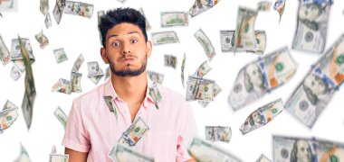 Yazlık tişört giyen yakışıklı Latin Amerikalı genç adam komik suratıyla yanaklarını şişiriyor. Havayla şişmiş ağız, çılgın bir ifade..