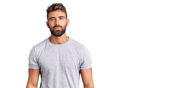 Günlük kıyafetler giyen genç İspanyol adam yüzünde ciddi bir ifadeyle rahatlamış. Basit ve doğal bir şekilde kameraya bakıyorsun.. 