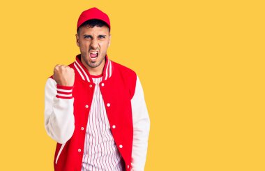 Beyzbol üniforması giyen genç İspanyol kızgın ve kızgın. Öfkeyle bağırırken yumruğunu sallıyor ve öfkeleniyor. öfke ve agresif konsept. 