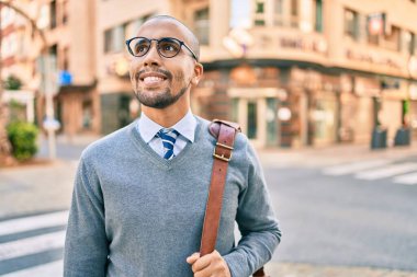 Genç Afrikalı Amerikalı iş adamı gülümseyerek şehirde mutlu bir şekilde yürüyor..