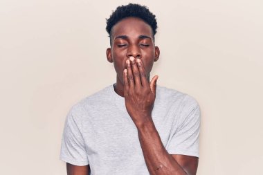 Gündelik giysiler giyen genç Afro-Amerikalı adam ağzını eliyle kapatmaktan sıkıldı. Huzursuz ve uykulu.. 