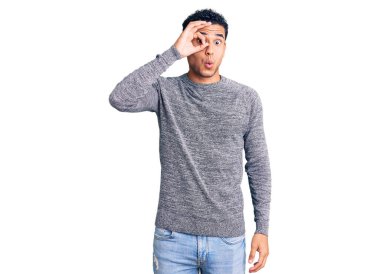 Latin asıllı yakışıklı genç adam sıradan bir süveter giyiyor. Şaşırmış yüz ifadesiyle şaşırmış, parmaklarından bakan gözler. İnançsız ifade. 