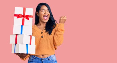 Uzun saçlı İspanyol kadın elinde hediyelerle gururla bağırıyor zaferi ve başarıyı kutluyor. Kollarını kaldırıp heyecanla bekliyor. 