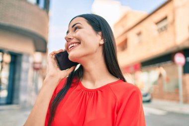 Genç Latin kız gülümsüyor. Şehirdeki akıllı telefondan konuşuyor..