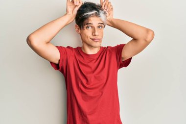 Gündelik kıyafetler giyen genç İspanyol adam boynuzlarını parmağında oynatarak komik hareketler yapıyor. 