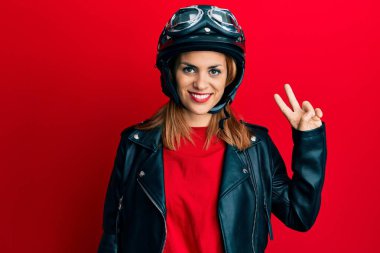 Motosiklet kaskı takan, gülümseyen, kameraya göz kırpan, zafer işareti yapan İspanyol genç bir kadın. İki numara.. 