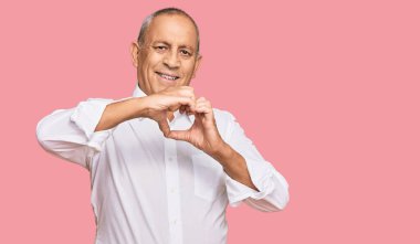 Yakışıklı, son sınıf öğrencisi, zarif, beyaz tişörtlü, aşıkken gülümseyen, elleriyle kalp sembolü yapan. romantik kavram. 