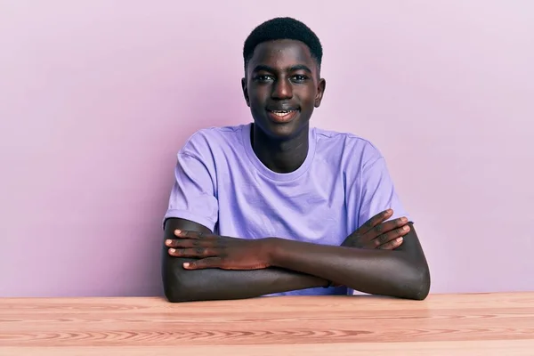 Młody Afrykański Amerykanin Ubrany Luźne Ubrania Siedzący Stole Uśmiechnięty Skrzyżowanymi — Zdjęcie stockowe