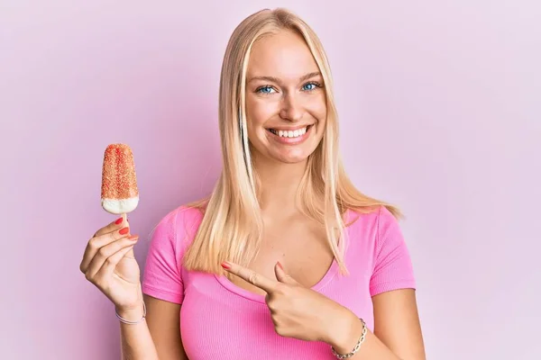 Young Blonde Girl Holding Ice Cream Smiling Happy Pointing Hand — ストック写真