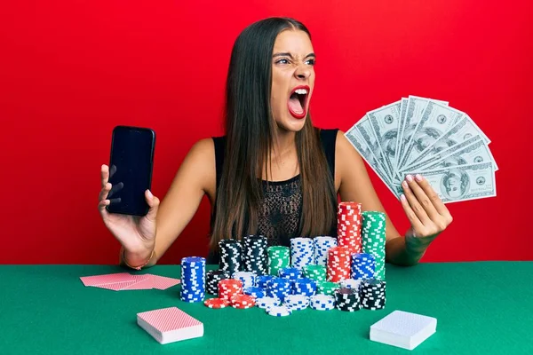 Jovem Hispânica Jogando Poker Segurando Smartphone Dólares Irritado Louco Gritando — Fotografia de Stock