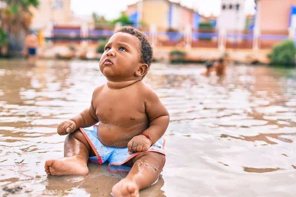 愛らしいアフリカ系アメリカ人の幼児がビーチに座っています — ストック写真