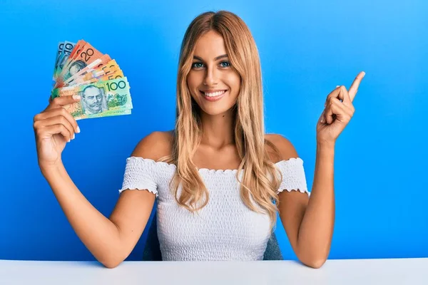 Hermosa Rubia Joven Sosteniendo Dólares Australianos Sonriendo Feliz Señalando Con — Foto de Stock