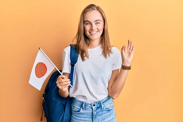 Hermosa Mujer Rubia Estudiante Intercambio Sosteniendo Bandera Japón Haciendo Signo —  Fotos de Stock