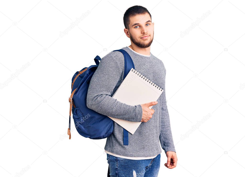 Young handsome man wearing student backpack holding notebook thinking attitude and sober expression looking self confident 