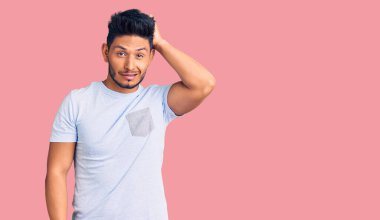 Gündelik kıyafetler giyen yakışıklı Latin Amerikalı genç adamın kafası karışıyor ve soru sormayı merak ediyor. Şüpheyle kararsız, kafa kafaya düşünerek. Düşünceli kavram. 