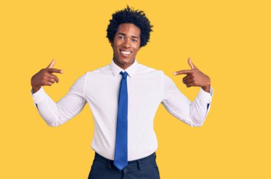 Afro saçlı, iş kıyafetleri giyen, kendine güvenen, kendini gururlu ve mutlu gösteren yakışıklı Afro-Amerikan erkeği.. 