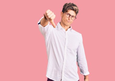 İş kıyafetleri ve gözlük takan genç yakışıklı adam mutsuz ve kızgın görünüyor. Reddedilmiş ve olumsuz jest yapıyor. kötü ifade. 