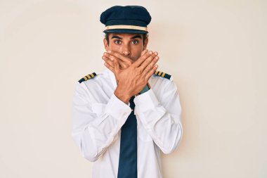 Uçak pilotu üniforması giyen genç bir İspanyol yanlışlıkla ağzı ellerle kapatmış. gizli kavram. 