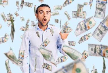 İş kıyafetleri giyen genç yakışıklı adam, elleri yana doğru işaret ederek şaşırdı, ağzı açık şaşkın bir şekilde ifade verdi..