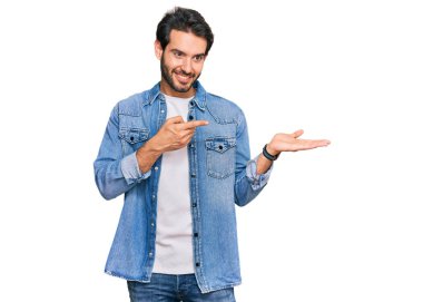 Gündelik kıyafetler giyen genç İspanyol adam kameraya hayret ediyor ve gülümsüyor.. 