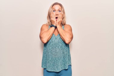 Orta yaşlı beyaz kadın spor kıyafetleri giyiyor. Korkmuş ve şok olmuş. Şaşırmış ve hayrete düşmüş. 