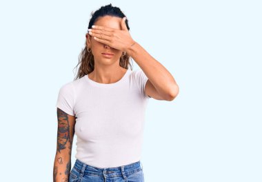 Gündelik beyaz tişörtler giyen, gözlerini kapayan, ciddi ve üzgün görünen İspanyol bir kadın. Görme, saklama ve reddetme konsepti 