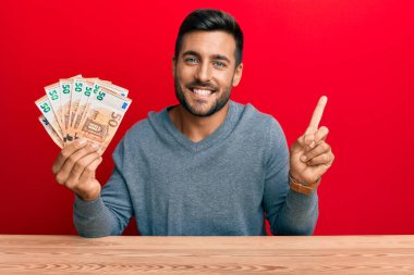 50 Euro 'luk banknotlar tutan yakışıklı İspanyol adam gülümsüyor. 